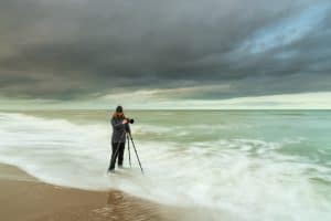 Natuurfotograaf stelt camera op statief scherp aan de kust.