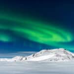 De ultieme gids voor het fotograferen van het noorderlicht Noorderlicht boven besneeuwde bergen op IJsland