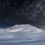 Startrail boven besneeuwde bergen