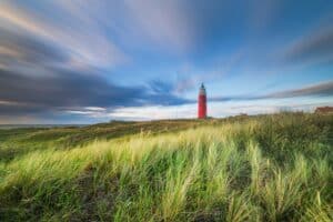 Scherpte en scherptediepte: hoe krijg je controle over wat scherp is en wat niet 7 Rode vuurtoren op een met gras begroeide duin.